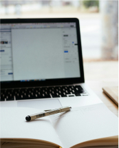 ノートパソコンの前に置かれたノートとペン